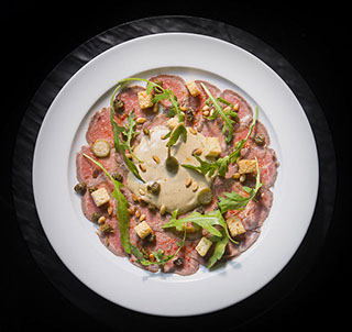 Carpaccio De File Tonnato - ao molho cremoso de atum, alcaparra, páprica, rúcula, pinole e crouton