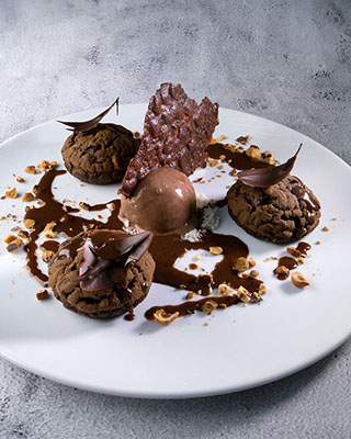 Profiteroles Nutella - de cacau recheados com creme de chocolate branco com raspas de limão siciliano, sorvete de chocolate belga e calda morna de Nutella